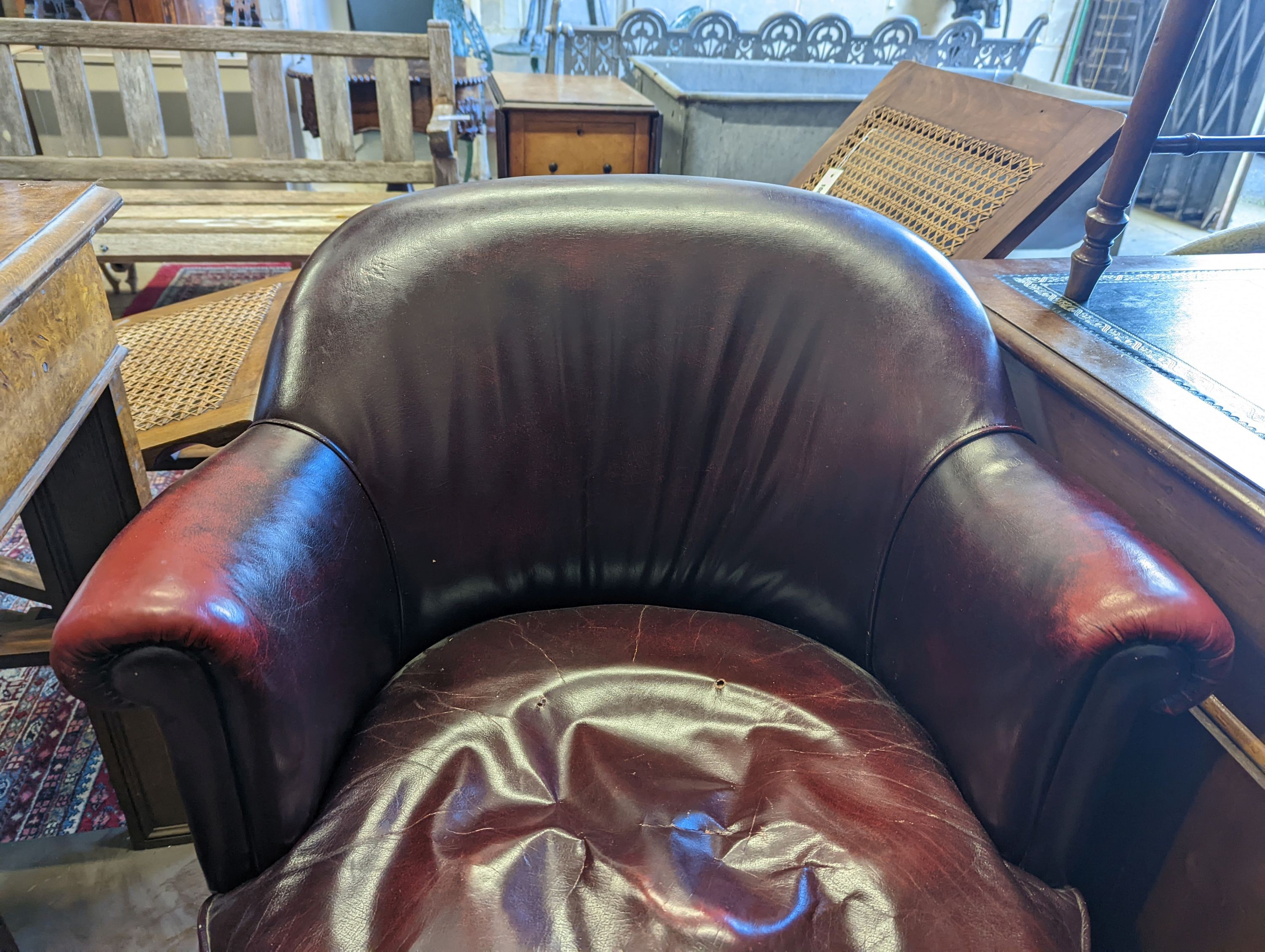 An early 20th century oak and burgundy leather tub framed swivel desk chair, width 70cm, depth 60cm, height 82cm